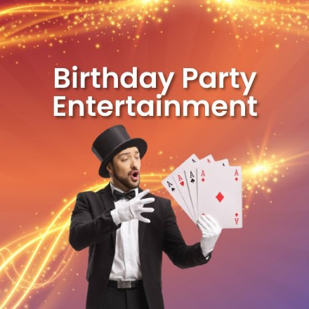 A professional magician in a tuxedo and top hat performing a card trick with four aces for a birthday party entertainment service offered in Gurgaon.