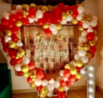 Heart-shaped balloon arch in red, white, and gold with a "Happy Anniversary" neon sign and a light-up '1', for a Romantic Anniversary Room Decor.