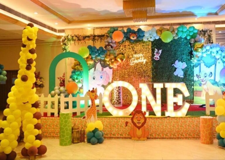 Jungle theme birthday decorations in Gurgaon by Adore Celebration, featuring balloon decoration, a giraffe, and "ONE" light-up letters.