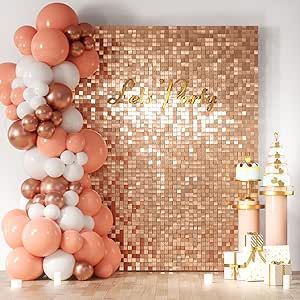 A glamorous party decoration setup featuring a square, shimmering rose gold sequin wall backdrop. On the left, there is a large balloon garland with rose gold, white, and chrome balloons. The words "Let's Party" are written in gold script on the backdrop. On the right, two pedestals display cakes.